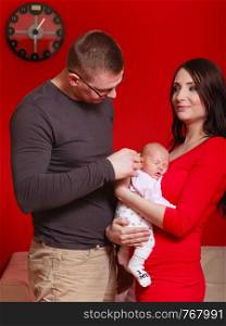 Adult and child relationship concept. Family photo of mother with little newborn baby and father, red background.. Family photo of mother, baby and father