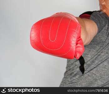 adult athlete in gray uniform and red leather glove strikes forward, white background