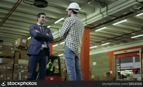 Adult business man in logistics facility talking to manual worker, staff people working in warehouse, men in industry. 1of19