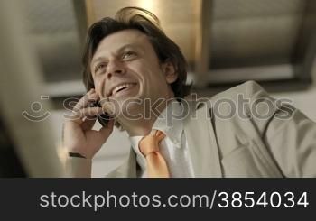 Adult businessman at work talking on mobile phone. Low angle view