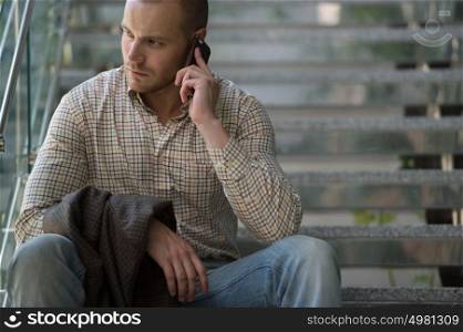 Adult businessman inside modern office building calling by mobile phone