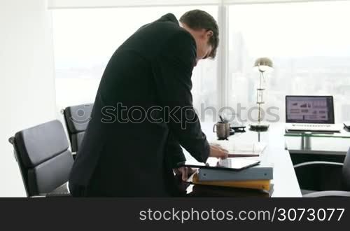 Adult businessman reviewing document on tablet pc. The man turns around and smiles at camera in portrait position. Medium shot
