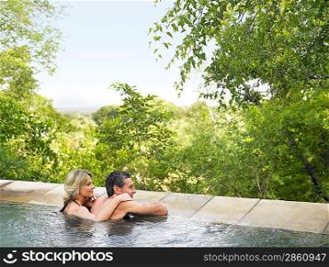 Adult couple in pool looking at view back view