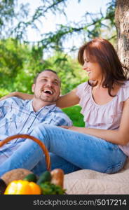 Adult couple picnicking in the summer park under the tree