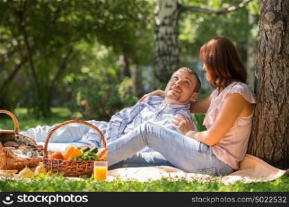 Adult couple picnicking in the summer park under the tree