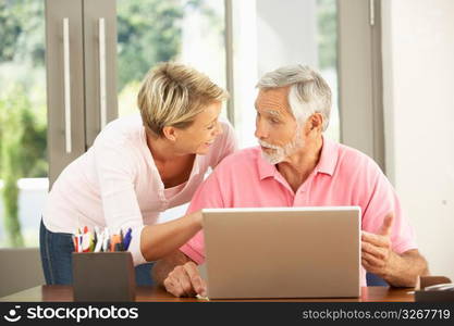 Adult Daughter And Senior Father Using Laptop At Home