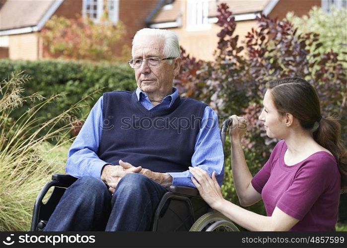 Adult Daughter Comforting Senior Father In Wheelchair