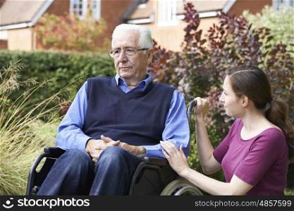Adult Daughter Comforting Senior Father In Wheelchair
