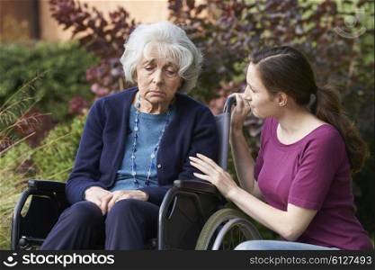Adult Daughter Comforting Senior Mother In Wheelchair