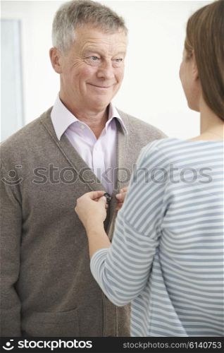 Adult Daughter Helping Senior Man To Button Cardigan