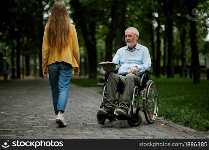 Adult disabled man in wheelchair asks for alms in park. Paralyzed people and disability, handicap overcoming. Handicapped male person needs help in public place. Adult disabled man in wheelchair asks for alms