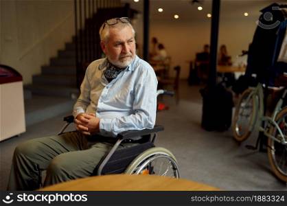 Adult disabled man in wheelchair, disability, cafeteria interior on background. Handicapped older male person, paralyzed people in public places. Adult disabled man in wheelchair, cafeteria