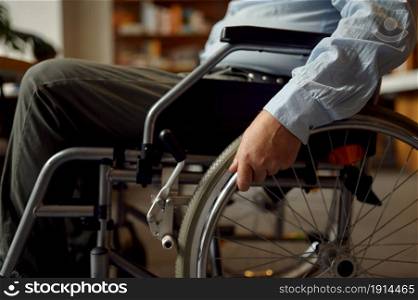 Adult disabled man in wheelchair, side view, disability, bookshelf and library interior on background. Handicapped older male person, paralyzed people get knowledge. Adult disabled man in wheelchair, disability