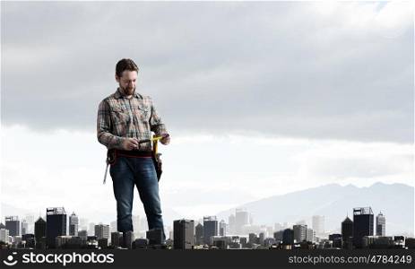 Adult engineer man. Builder man in checked shirt with tool belt on waist