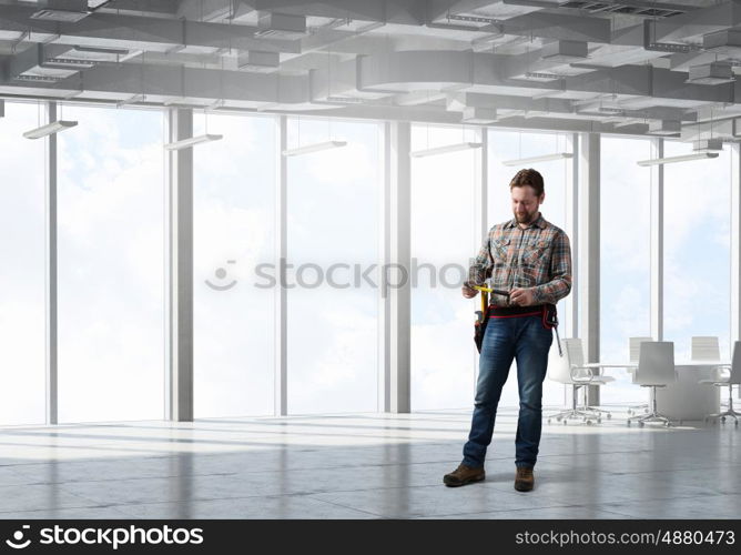 Adult engineer man. Builder man in checked shirt with tool belt on waist