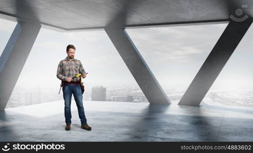 Adult engineer man. Builder man in checked shirt with tool belt on waist