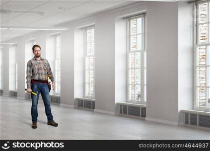 Adult engineer man. Builder man in checked shirt with tool belt on waist. Mixed media