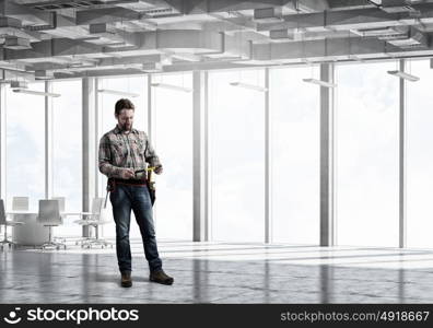 Adult engineer man. Builder man in checked shirt with tool belt on waist. Mixed media