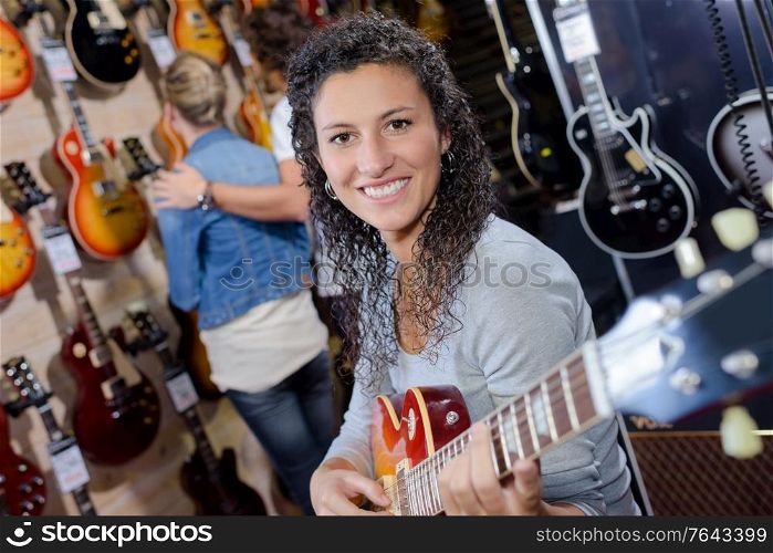 adult female customer trying to play new guitar in store