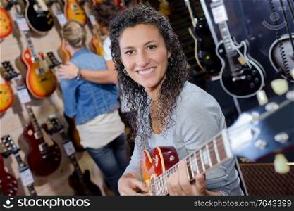 adult female customer trying to play new guitar in store