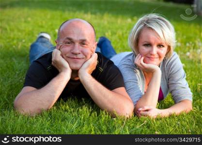 Adult happy couple together lying on grass