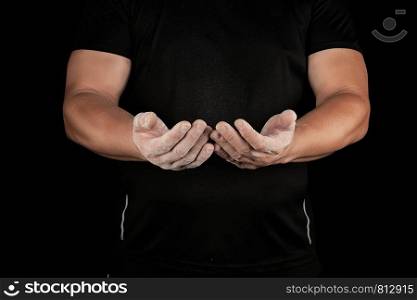 adult male athlete rubs white powder with magnesia before sporting events, black background