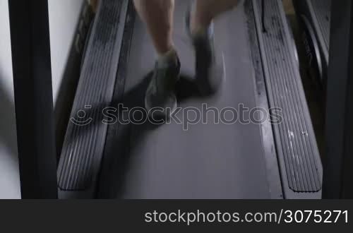 Adult male in sneakers walking on a treadmill and then begins to run. Feet closeup