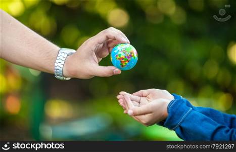 Adult man giving Earth globe to little girl