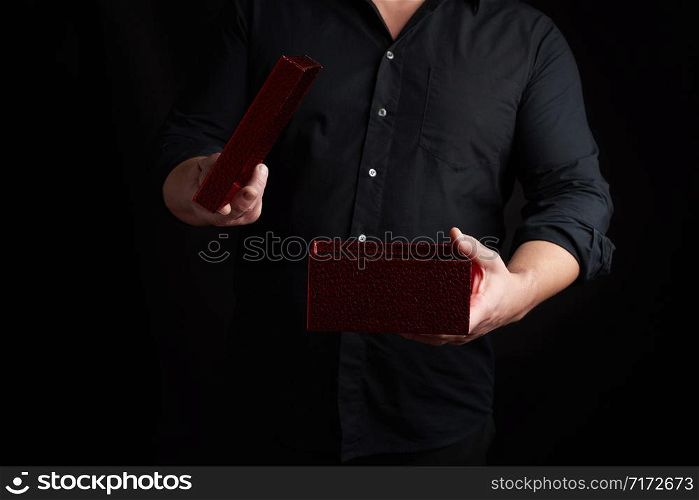adult man in a black shirt holds an open shiny red cardboard box, concept of surprise and holiday greetings