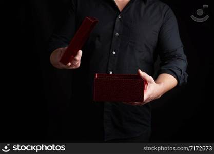 adult man in a black shirt holds an open shiny red cardboard box, concept of surprise and holiday greetings