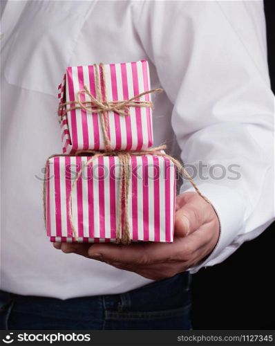 adult man in a white shirt holds a pink gift cardboard box, concept of a congratulation on the holiday, anniversary, surprise