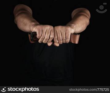 adult man in black clothes holding a brown leather belt with an iron buckle, concept of violence and aggression
