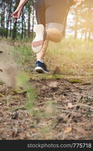 adult man in black shorts runs in the coniferous forest against the bright sun, concept of a healthy lifestyle and running in the fresh air