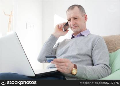 Adult man reading a credit card number during phone call