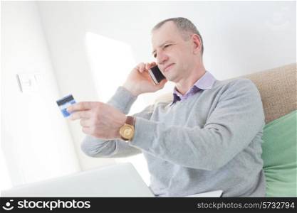 Adult man reading a credit card number during phone call