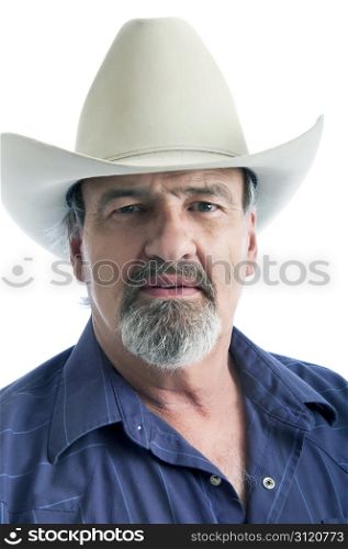 Adult man wearing a cowboy hat looking sternly at the camera. Cowboy with beard