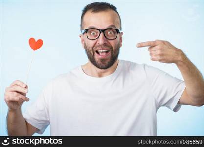Adult man wearing eyeglasses being in love holding small red shape heart on stick. Romance, flirting, Valentines Day concept.. Adult man with heart on stick