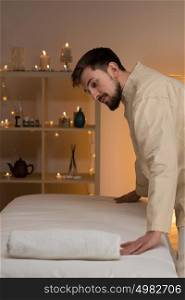 Adult masseur at spa or beauty salon preparing couch for working