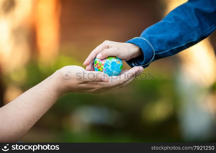 Adult men hand and little girl hands holding planet Earth
