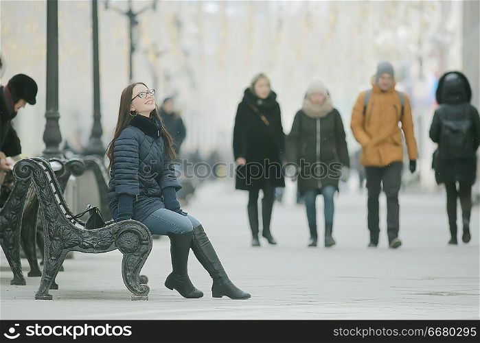adult model girl in a coat on a winter walk in the city / Christmas vacation city tour