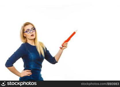 Adult person pensive serious blonde student girl or business woman female teacher wearing nerdy glasses holding big red pencil. Studio shot on white.. Serious woman holds big pencil in hand