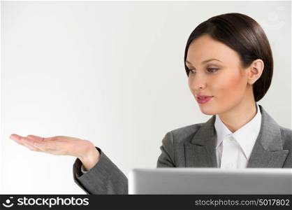 Adult pretty business woman making presentation of new product. Blank copyspace above her arm