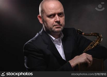 Adult saxophone musician looking at the camera, gray background