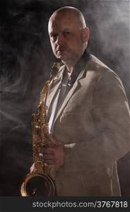 Adult saxophone musician looking at the camera, smoky background