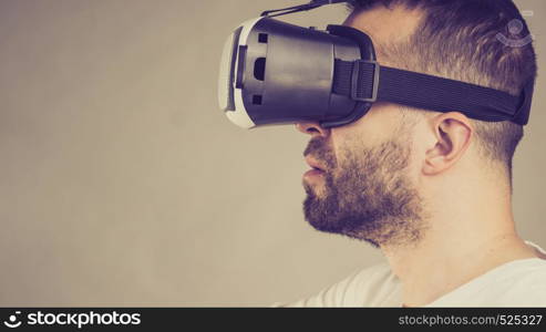 Adult short bearded guy exploring virtual reality wearing VR goggles being into technology. Studio shot side view.. Adult man wearing vr goggles