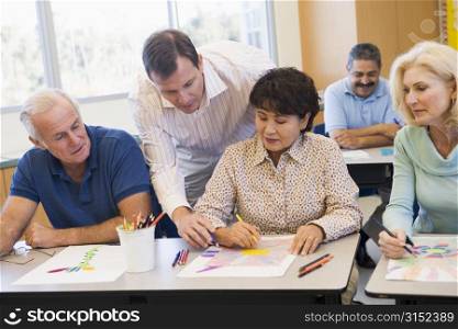 Adult students in class drawing pictures with teacher helping (selective focus)