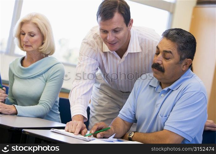 Adult students in class with teacher helping
