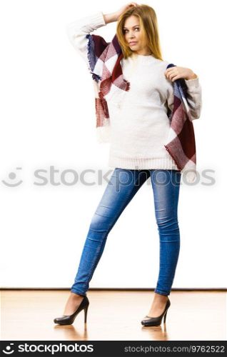 Adult woman wearing fashionable autumn outfit, white sweater, blue jeans and long beautiful warm colorful soft scarf.. Woman wearing warm soft scarf