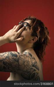 Adult woman with tattoos rubbng her eyes.