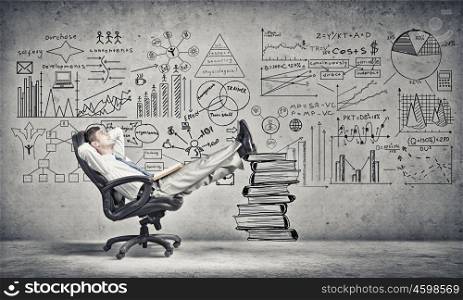 Advantage of education and books reading. Young handsome businessman sitting in chair with his legs on pile of books